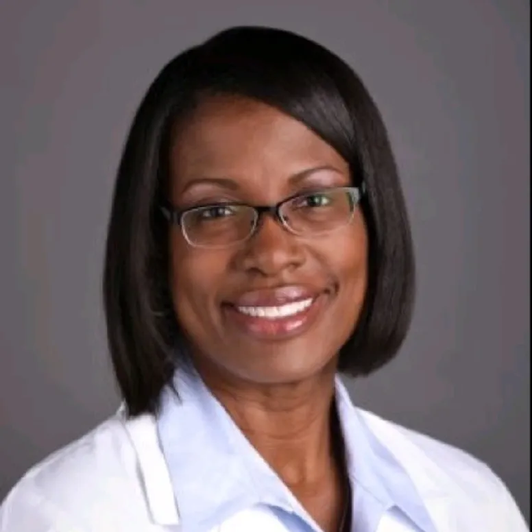 Woman in lab coat smiling confidently.